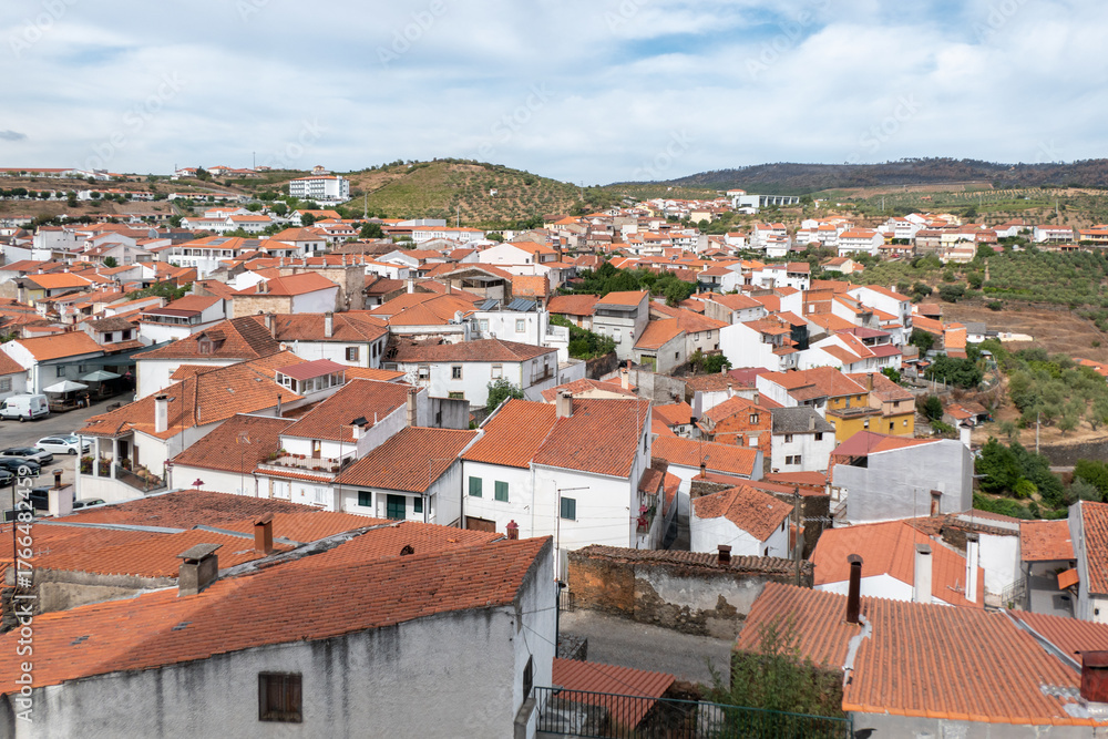 Fototapeta premium Vista panorâmica da vila manuelina de Freixo de Espada à Cinta em Trás-os-Montes, rodeada por uma paisagem montanhosa sob um céu parcialmente nublado em Portugal