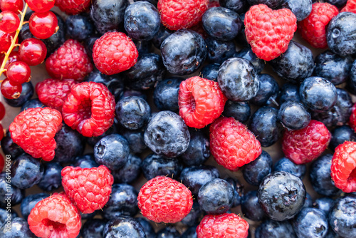 A plate with berries. Blackcurrants, raspberries and blueberries top view.