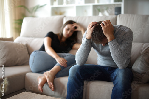 Bild auf Leinwand Desperate man suffering beside his sad wife at home