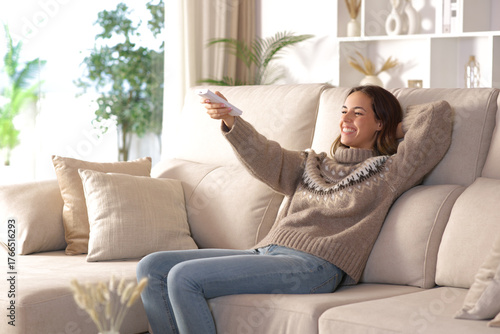 Happy woman relaxing at home turning on heater
