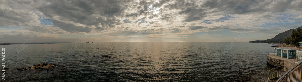 Obraz premium ampia composizione panoramica con vista sul Golfo di Trieste, dalla costa vicino alla città, in primavera, di pomeriggio tardi, con mare calmo e cielo nuvoloso