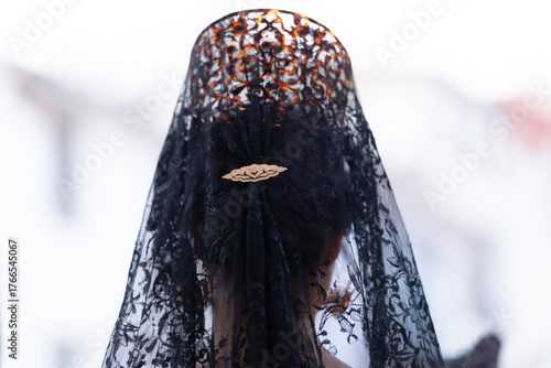 Peinado de mujer con peineta y mantilla negra y dorada en la cabeza