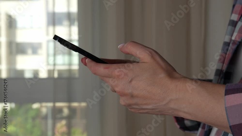 Woman using smartphone pressing fingerers, reading social media internet, typing text or shopping online. A close-up of hands holding a smartphone at home or work. 