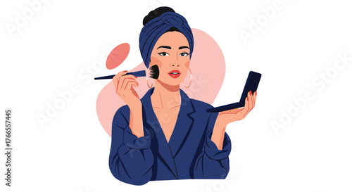 A stylish woman in a blue turban applies blush with a brush while holding a compact mirror, getting ready for the day.
