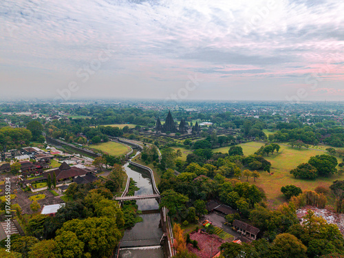 Aerial view of the majestic Prambanan Temple amidst a sea of green trees, with a tranquil river snaking through the landscape, Yogyakarta, Daerah Istimewa Yogyakarta, Indonesia.