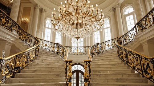Elegant marble staircase with ornate golden railings and sunlight
