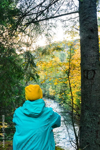 A female tourist looking at a mountain river against the backdrop of an autumn landscape, hiking in the mountains