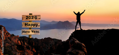 2026 hapy new year written on wooden post sign and silhouette of hiker with t...