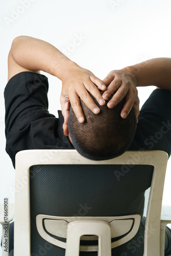 Stressed businessman leans back in chair with hands on head seeking relief from work pressures now