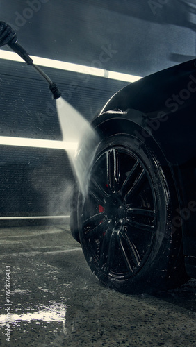 Foto Closeup of car wheel being cleaned with high pressure water jet