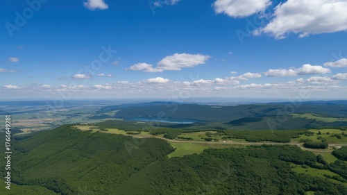 Breathtaking aerial view of the green mountain range and valley under a cloudy blue sky