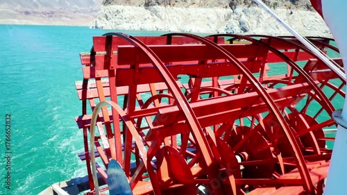 Red paddle wheel rotating on a paddle steam boat on a lake