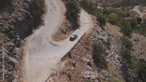 Summer drone footage of car on serpentine coastal road in Greece