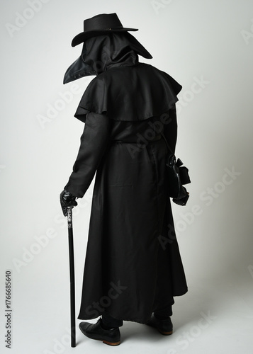 Plague Doctor Walking Away, Full length Silhouette Portrait of Gothic Halloween Character with Beak Mask, Black Cloak, Walking Stick on White Studio Background, Dramatic Dark Costume and Fantasy Horro