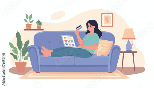 A young woman is relaxing comfortably on a blue sofa, holding a credit card and browsing an online store on her laptop, showcasing the convenience of modern e-commerce and digital shopping from home.