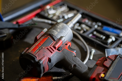 Slika na platnu Professional cordless impact wrench with red and black housing resting on mechan