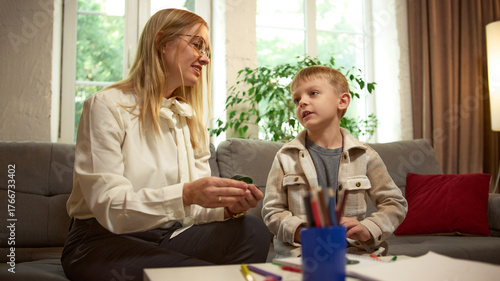Female psychologist encouraging boy during child therapy session. Concept of emotional intelligence, family psychology, child development support for education and healthcare materials.