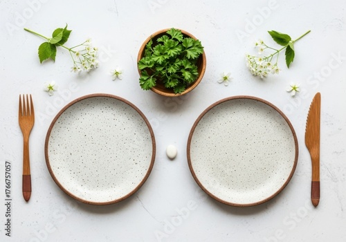 Table setting for two with plates, cutlery, and fresh herbs