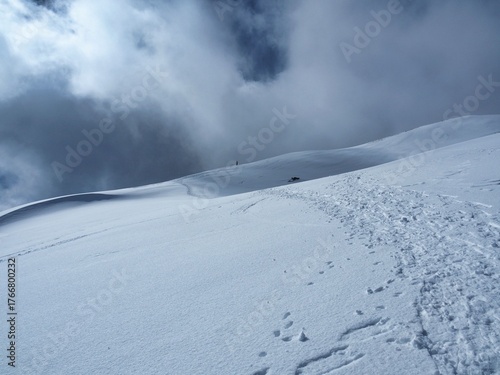 Snowy Trail Ascending Mountain Slope Under Dramatic Sky