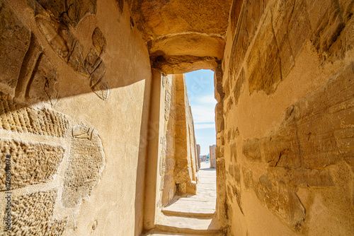 A sunlit narrow stone hallway inside the Temple of Karnak in Luxor Egypt. The carved walls and bright exit evoke history mystery and adventure.