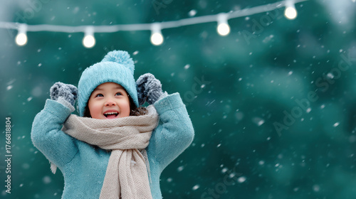 Joyful child in winter attire celebrating Christmas with snow and festive lights in background