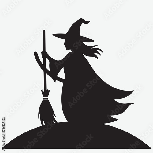 Silhouette of a witch with a broomstick on a hill