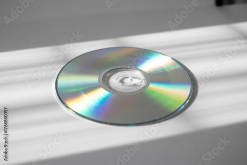 Compact disc reflecting light on a white surface creating a modern minimalist look