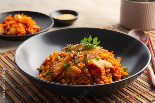 Kimchi fried rice with pork belly topped with sesame seed and Crispy Seaweed in black plate.Korean food.
