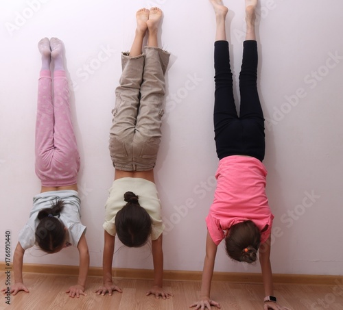 Children standing on their hands during a gymnastic or fitness exercise. Concept of strength, balance, coordination, and childhood physical activity.