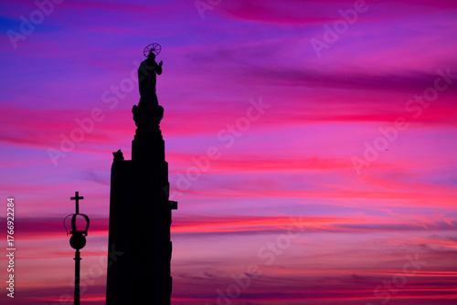 The silhouette of a religious statue stands against a winter sunset, where deep blues and soft pinks blend into violet. Sameiro Sanctuary, Braga, Portugal.