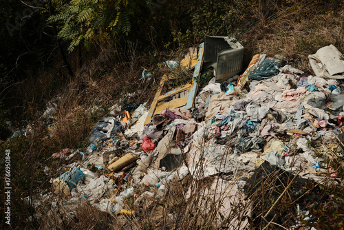 фотографія Pile of plastic waste and discarded clothes on illegal dump site in mountain are