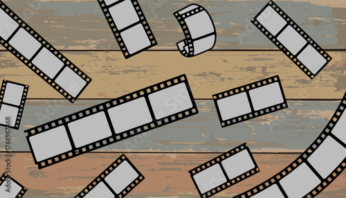 Scattered vintage film strips with blank frames lie on a distressed wooden background, evoking a sense of nostalgia and the art of filmmaking, perfect for movie-related projects and graphic design.