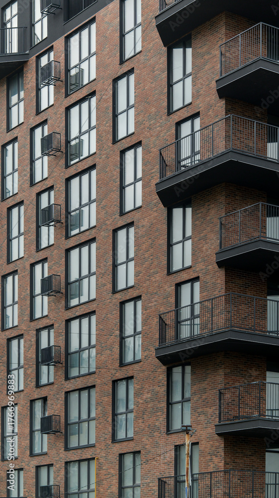 Fototapeta premium Modern apartment building exterior with brick facade and balconies