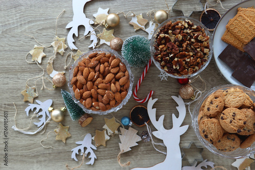 Various Christmas decorations, cookies, chocolate and nuts on wooden background. Flat lay.
