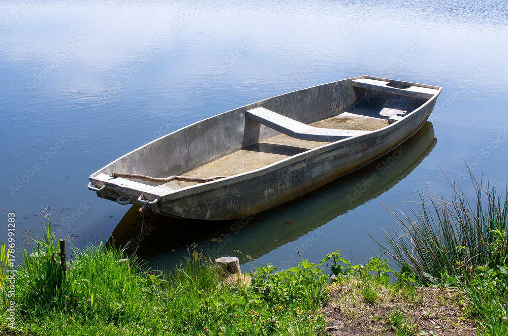 Obraz premium Peaceful rowboat rests on calm waters in sunlit scene