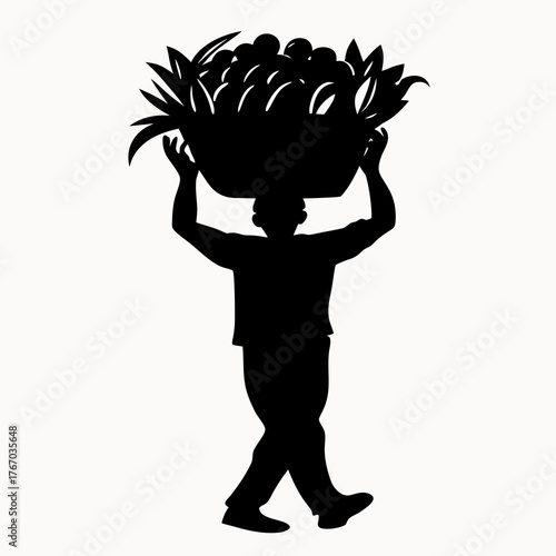 Silhouette of a man carrying a basket of fruits on his head with both hands in a black and white image
