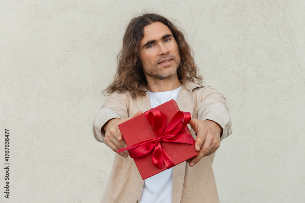 Fototapeta premium Happy handsome caucasian man giving red gift box with love. Birthday. Romantic surprise and celebration. Greeting card.
