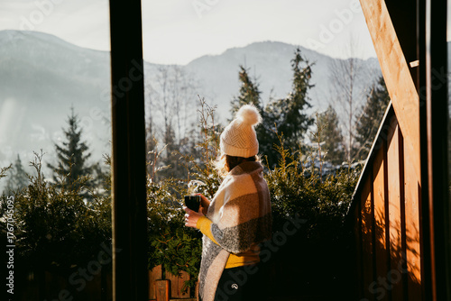 Fototapeta woman enjoying hot cup of tea on terrace in winter mountains ski holiday lodging