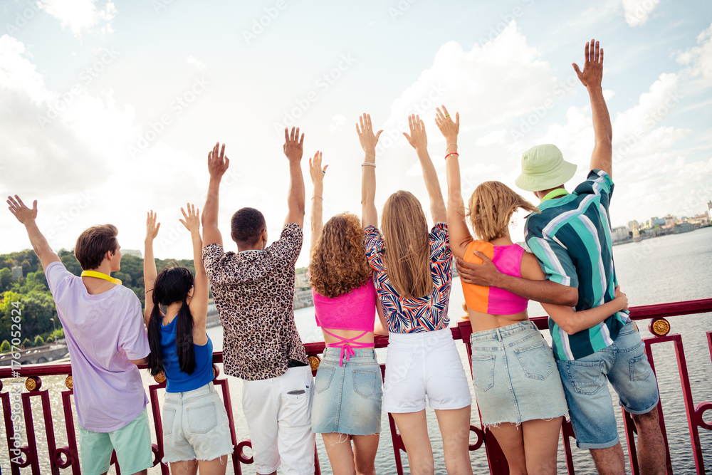 Fototapeta premium Group of young friends enjoying a summer day outdoors while taking in a scenic urban water view, celebrating friendship