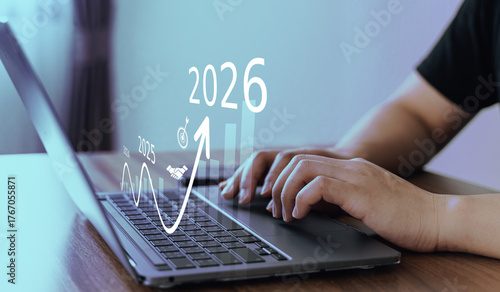 Close-up of hands working on laptop with futuristic financial graphs and projections for 2026, symbolizing growth and analytics.
