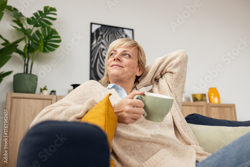 Woman relaxing at home, enjoying coffee, daydreaming