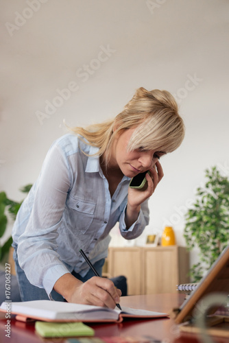 Woman multitasking working from home talking on phone