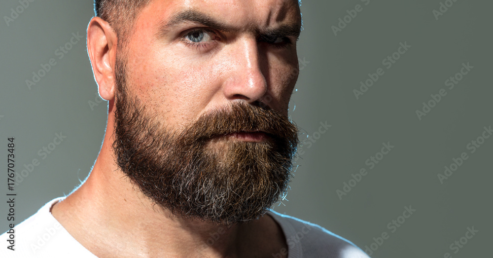 Obraz premium Closeup portrait of bearded man. Serious fashion male model. Handsome man with stylish beard and mustache in casual wear. Cropped portrait of bearded male hipster after barbershop service. Copy space.