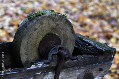 an old, moss-covered grindstone set in a weathered wooden frame