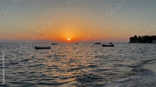 Silhouettes of boats on the background of sunset. Aegean Sea in Greece, Halkidiki. Panorama of sunset at sea. Fishing  boats swaying on the sea waves. 
