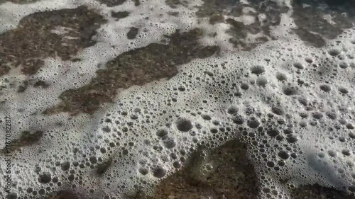 Foamy sea waves crashing against the sandy shore. Aegean Sea in Greece