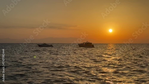  Silhouettes of boats on the background of sunset. Panorama of sunset at sea. Fishing boats swaying on the sea waves.Aegean Sea in Greece, Halkidiki