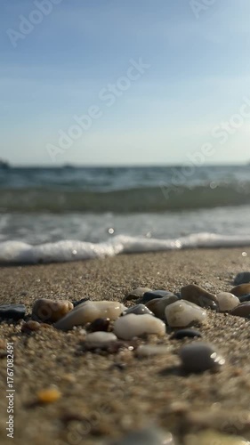 Sea pebbles close-up on  a sandy shore washed by sea waves. Aegean Sea in Greece, Halkidiki