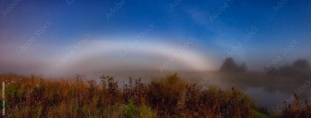 Naklejka premium a rare optical phenomenon: a foggy moonbow in a field
