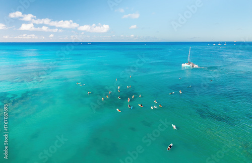 Aerial pic of surfers seating on surfboards and waiting for wave in the middle of ocean with perfect weather and clean water at sunset time in Hawaii paradise, shot on drone from above	
